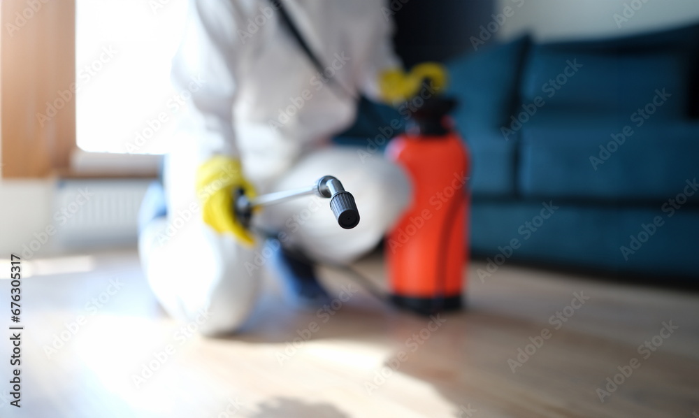 Prevention of spread of virus and rodents indoors. Disinfectant in protective suit and mask sprays disinfectants in home or office concept