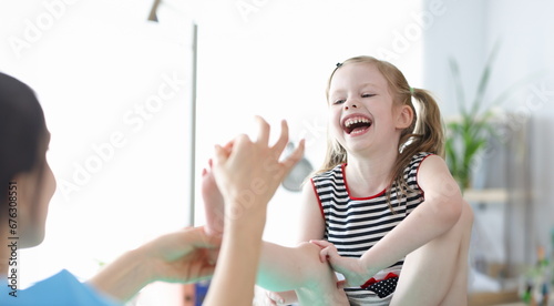 Little laughing girl at doctor appointment showing her foot. Foot massage for children concept