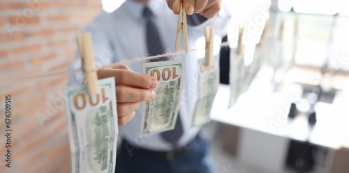Man hanging american dollar bills on rope closeup. Laundering of money concept