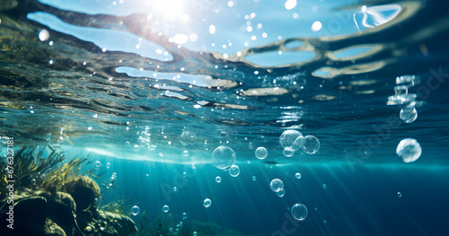 Air bubbles ascend in clear blue water, catching the light on their way to the surface.