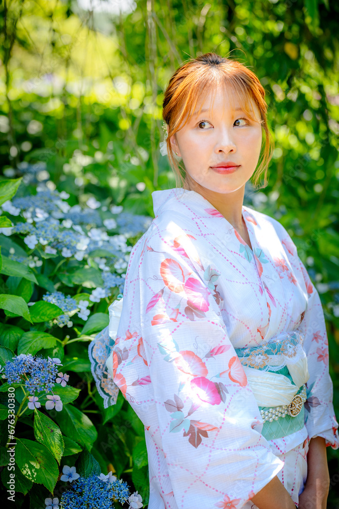 Portrait of a young woman wearing a Japanese yukata summer kimono in a hydrangea garden. Kyoto, Japan. soft blur background. Portrait of a young woman wearing a Japanese yukata summer kimono in a hydrangea garden. Kyoto, Japan. soft blur background.
