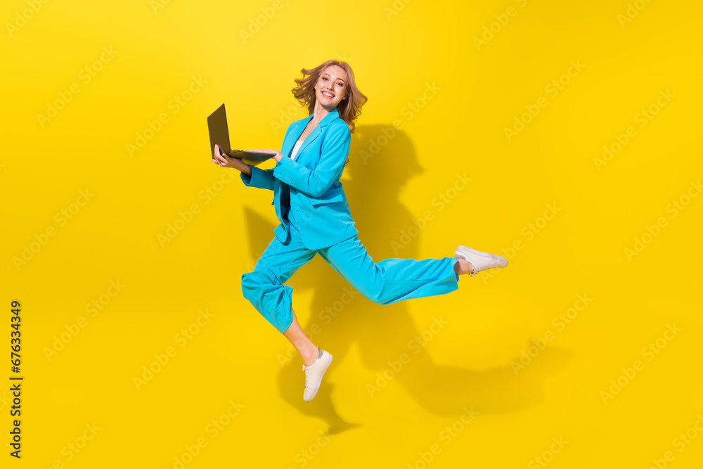 Full length photo of intelligent woman wear blue stylish suit hold laptop write enjoy fast speed internet isolated on yellow background