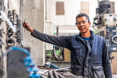 Latino worker in the metal industrial factory trade in the numerical control sector, picking up tools