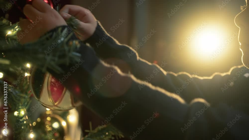 Kid decorating christmas tree with balls 
