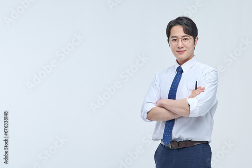 A young, handsome Asian man wearing glasses and a dress shirt and tie is holding a pen and explaining about business.