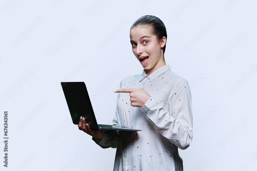 Teenage girl student using laptop, on white background, pointing at screen Teenage girl student using laptop, on white background, pointing at screen