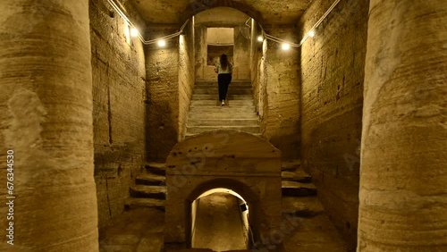 Travel girl explores catacombs of Kom El Shoqafa in Alexandria Egypt. Woman upstairs in Mysterious cave photo