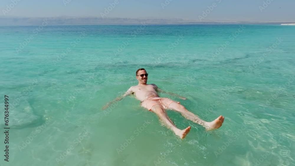 Happy Tourist Lays Down in Dead Sea and Floats Easily. Famous Salty Lake. Israel Happy Tourist Lays Down in Dead Sea and Floats Easily. Famous Salty Lake. Israel
