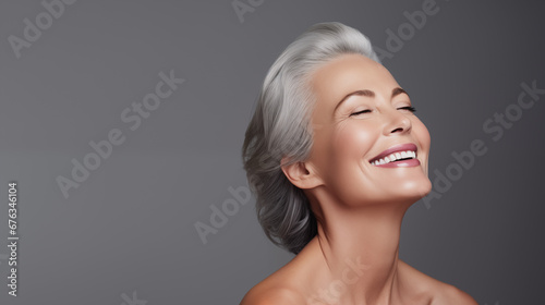 Beautiful aging young looking and smiling woman. Advertising concept for cosmetics and beauty products. Gray hair and healthy skin.