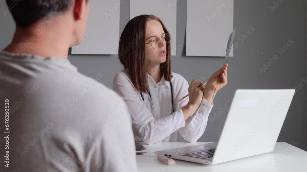 X-ray examination. Woman doctor surgeon holding film scan radiography diagnostic in hospital bone disease treatment explaining it for unrecognizable man patient. X-ray examination. Woman doctor surgeon holding film scan radiography diagnostic in hospital bone disease treatment explaining it for unrecognizable man patient.