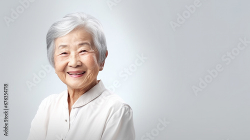 Radiant senior woman with silver hair smiling gently on a light background..