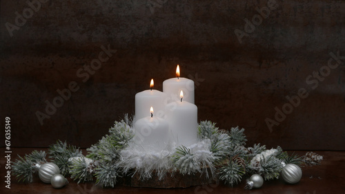 Festlicher geschmückter Adventskranz mit vier weißen brennenden Kerzen vor einem dunklem Hintergrund mit Platz für Text.