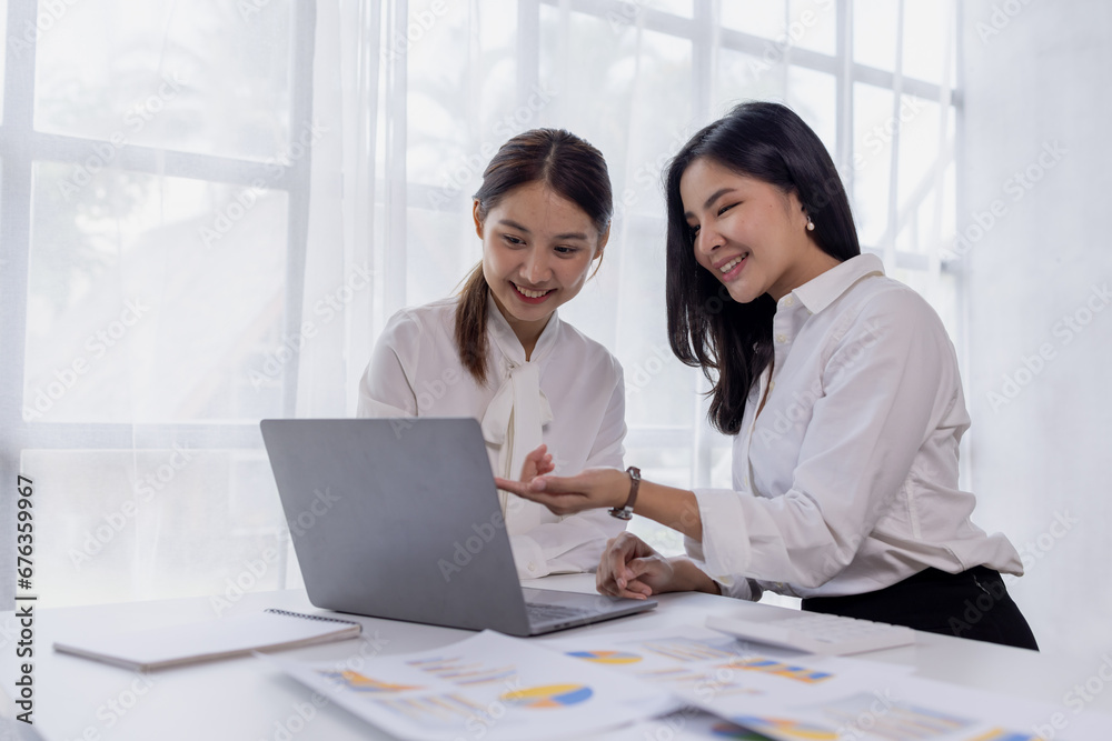 Two asian confident business women point to graphs and charts to analyze market data, balance sheet, account, net profit to plan new sales strategies to increase production capacity. Two asian confident business women point to graphs and charts to analyze market data, balance sheet, account, net profit to plan new sales strategies to increase production capacity.