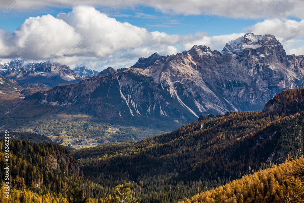 Spectacular autumn landscape of golden trees and large snow-capped mountains in the Dolomite Alps. Ampezzo Valley and the Sorapiss group