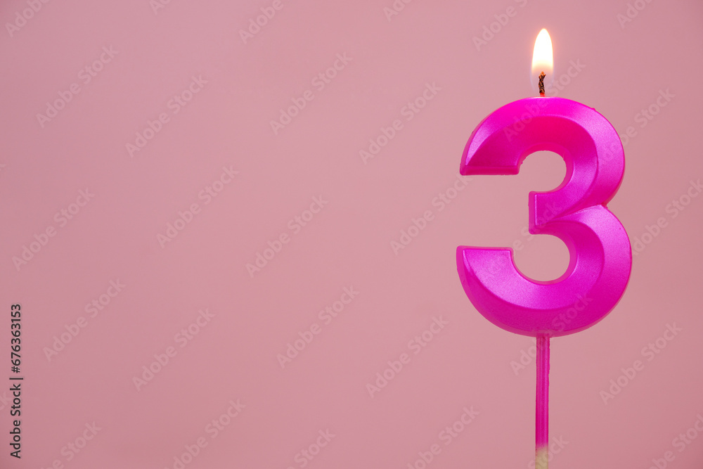 Pink birthday candle, number 3, burning on pink background. Copy space for text. Pink birthday candle, number 3, burning on pink background. Copy space for text.