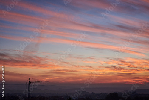 An amazing landscape view at sunrise with red orange blue vivid sky. Natural background with suburbs of the city and beautiful;fields. Nature conservation concept. Eco friendly. Universe.