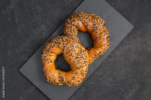 Tasty fresh toasted bagels sprinkled with white and black sesame seeds on a dark background. Turkish bagels or simits - traditional bakery. Top view, copy space
