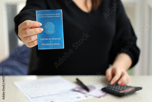 Woman boss gives a brazilian work card and social security blue book to us in employment office close up photo