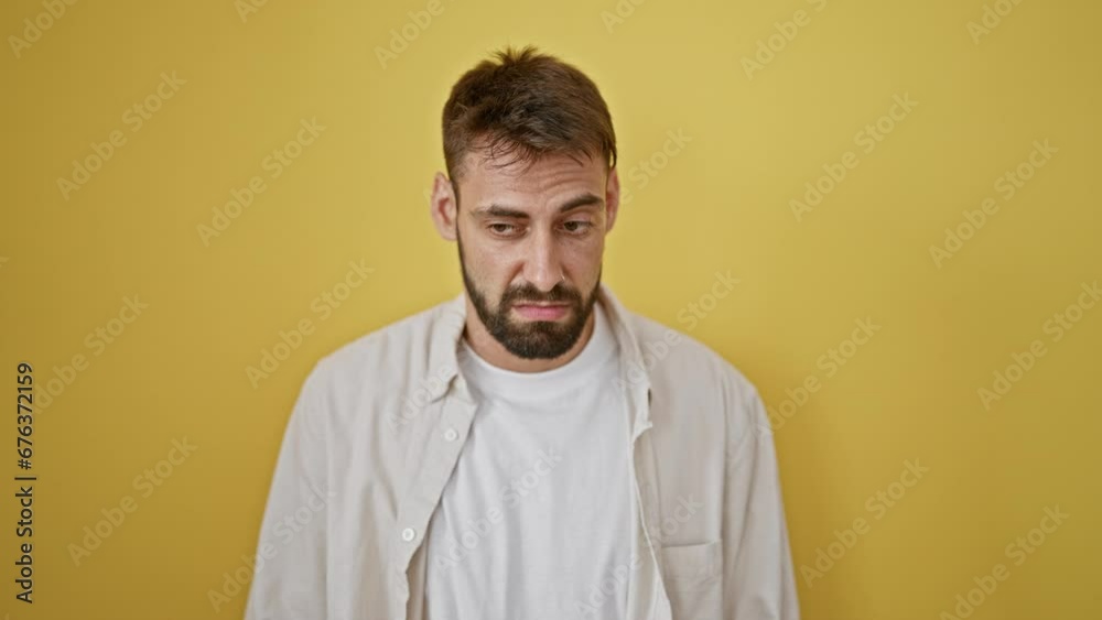Cool and casual young hispanic man oozing serious, relaxed concentrate expression, looking handsome with beard, standing alone against isolated yellow wall background. male adult lifestyle portrait. Cool and casual young hispanic man oozing serious, relaxed concentrate expression, looking handsome with beard, standing alone against isolated yellow wall background. male adult lifestyle portrait.