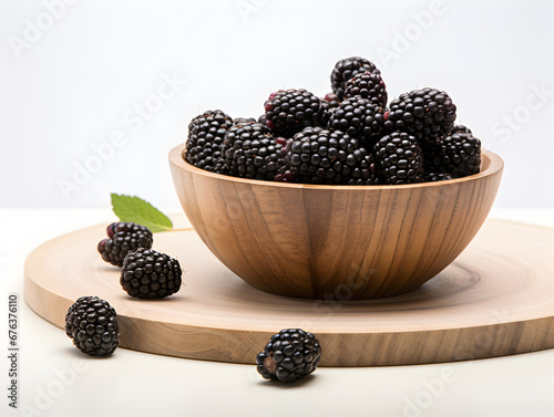 Fresh and ripe blackberries in a wooden bowl on white background 