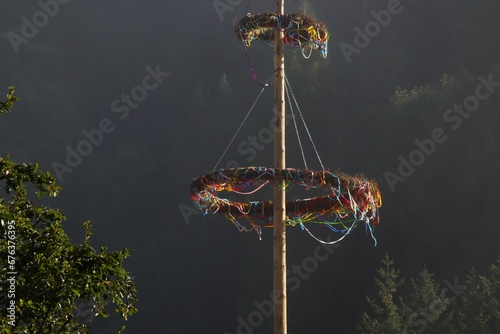 wooden maypole in front of trees and mountains