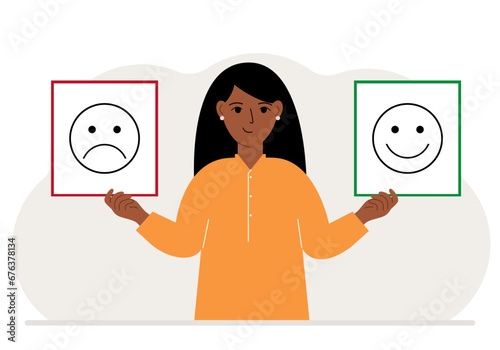 Smiling woman holds a card with a sad emoji in one hand and a smiling emoji in the other hand. The concept of emotions, masks or psychological help.