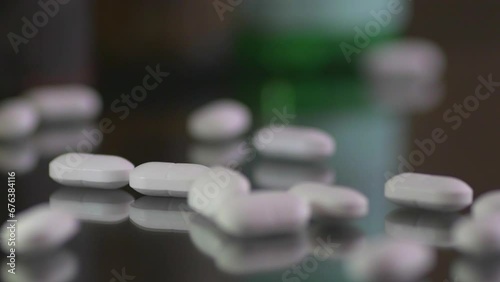 White pills dropping on a table surface, close up. 