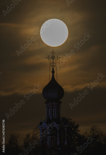 A big yellow moon shines over the church