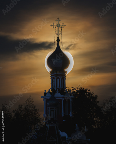 A big yellow moon shines over the church
