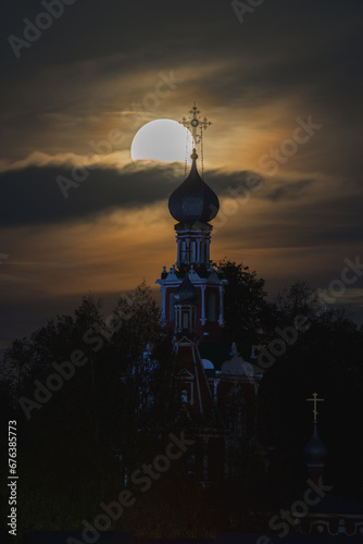 A big yellow moon shines over the church