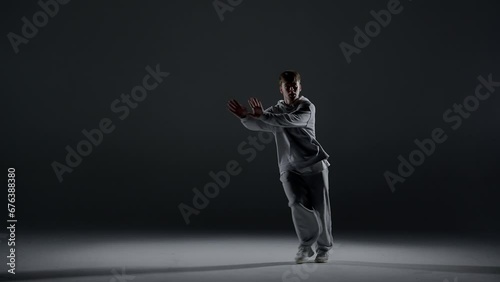 Wallpaper Mural The young man stands on a dark background. He is illuminated by a white light from below. Creates a light haze. Demonstrates a dance hip hop movement. It is plastic and rhythmic. Torontodigital.ca