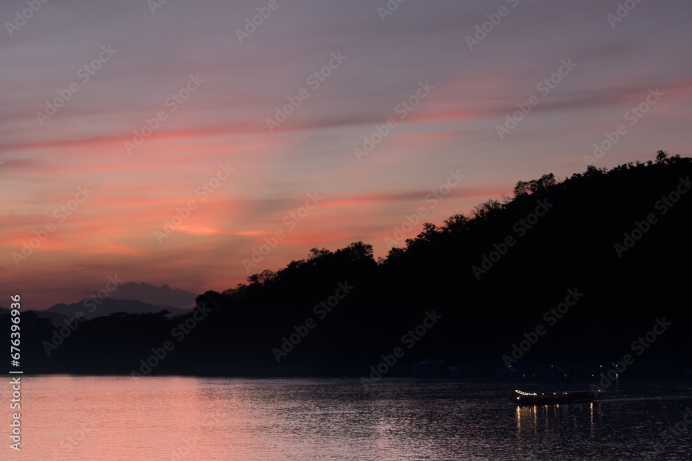 Boat sailing on the Mekong river during the sunset in Luang Prabang Boat sailing on the Mekong river during the sunset in Luang Prabang