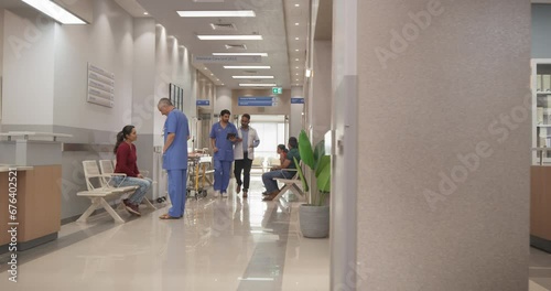 Tracking Dolly Shot of Hospital Corridor and Lobby Filled with Group of Diverse Indian Patients Waiting for their Appointments. Modern Health Clinic with Active Doctors, Nurses and Staff Working