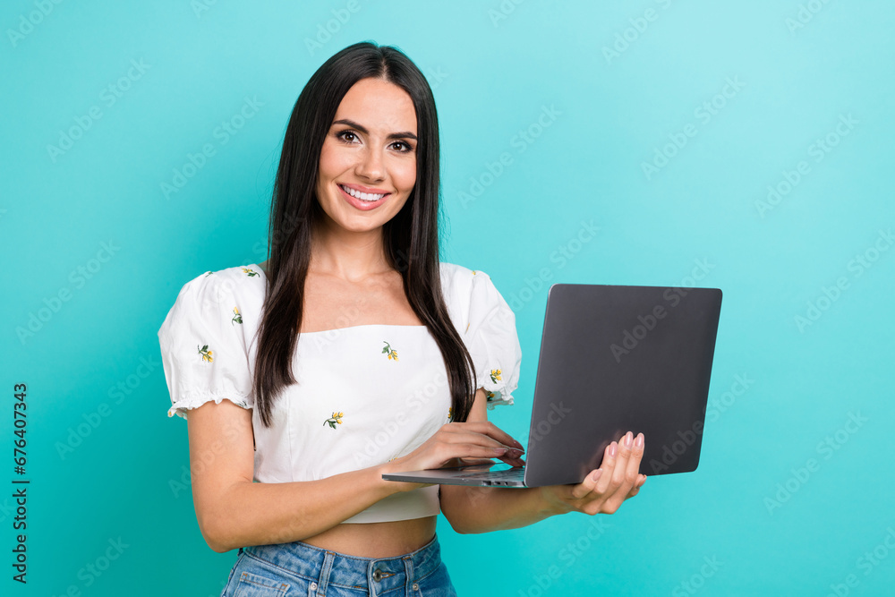 Closeup portrait of nice young girl brunette holding laptop trying new device light weight macbook isolated on aquamarine color background Closeup portrait of nice young girl brunette holding laptop trying new device light weight macbook isolated on aquamarine color background