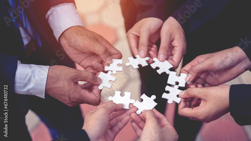 The hand of a businessman holding a paper jigsaw And solve the puzzle together. The business team assembled a jigsaw puzzle. A business group wishing to bring together the puzzle pieces