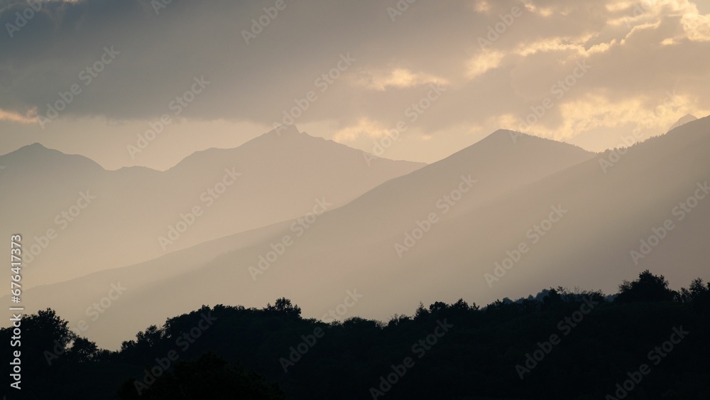 Silhouette of mountains in sunset light with some misty fog Silhouette of mountains in sunset light with some misty fog