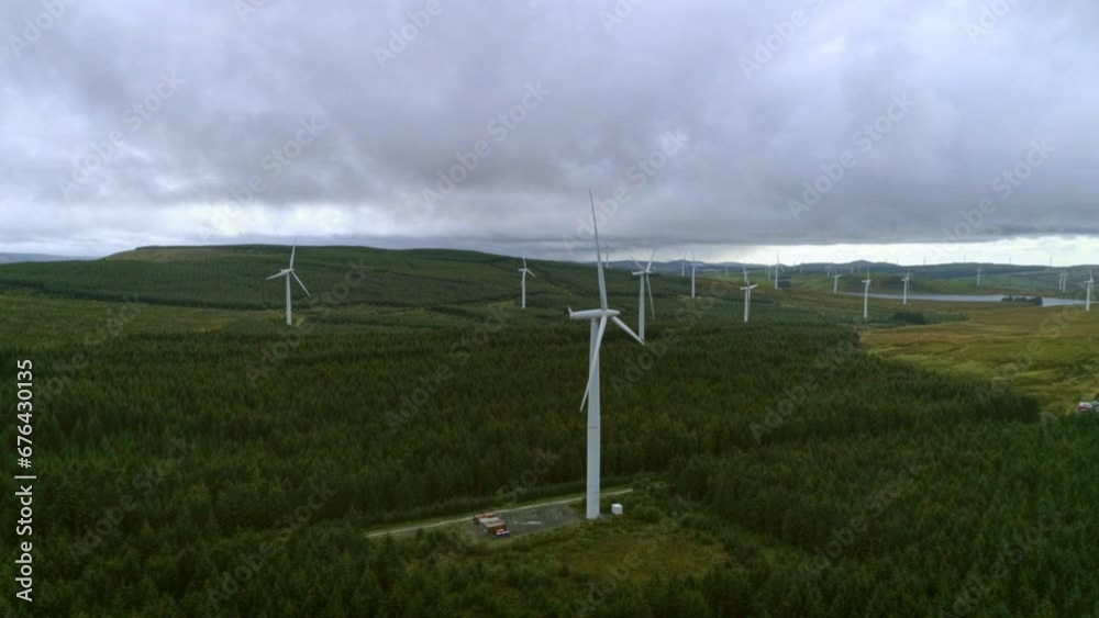 Aerial drone push in of windmill farm for energy production on beautiful cloudy sky in highlands. Wind power turbines generating clean renewable energy for sustainable development Aerial drone push in of windmill farm for energy production on beautiful cloudy sky in highlands. Wind power turbines generating clean renewable energy for sustainable development