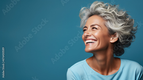 A happy elderly lady isolated on a turquoise background © jr-art