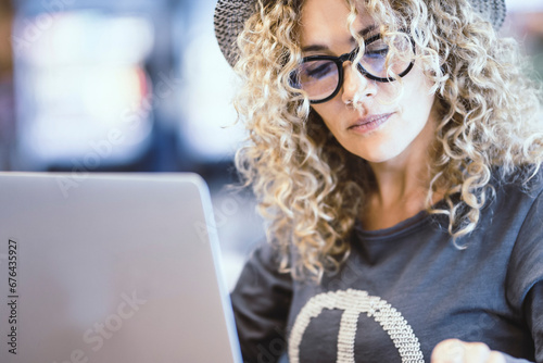 Portrait of woman working with computer in a cafe or airport gate station. Digital nomad and modern worker. Female people using notebook and phone in alternative office. Pretty lady with eyewear photo