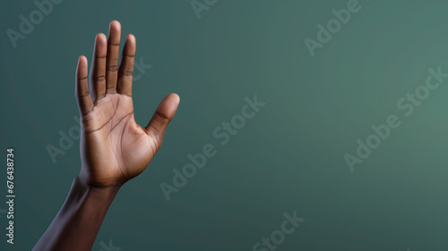 Open hand raised against a teal background, symbolizing openness, aid. photo