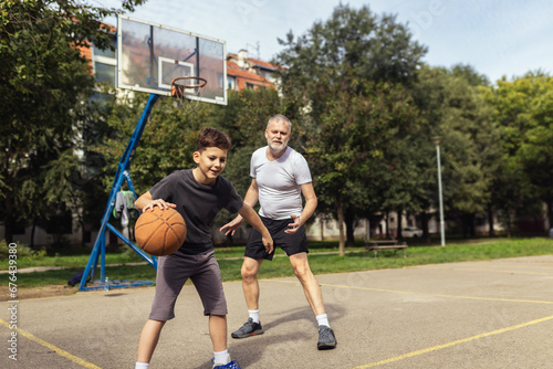 Mature man playing basketball with his son