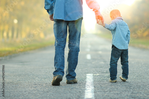 A Happy parent with child are walking along the road in the park on nature travel