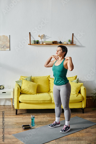 attractive sporty woman with short hair in sportswear exercising actively with hands on shoulders © LIGHTFIELD STUDIOS