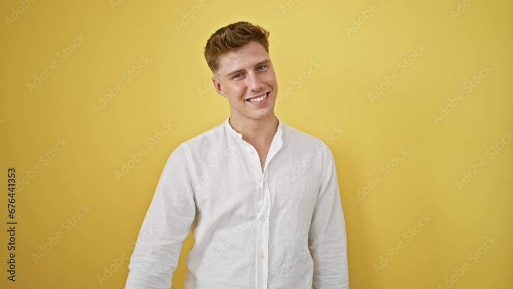 Joyful and confident caucasian man saluting with his fingers, smiling brightly against an isolated yellow background Joyful and confident caucasian man saluting with his fingers, smiling brightly against an isolated yellow background