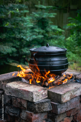Vertical shot of an old cooking pot placed on the fire in a brick stove outdoors