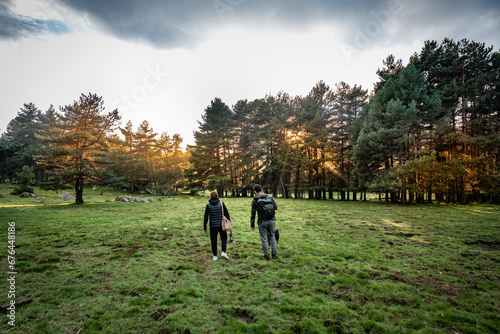 Young adults stroll through a large green meadow in autumn photo