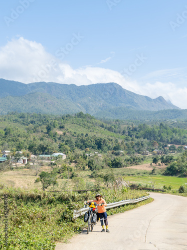 Traveler woman pushes her heavy bicycle loaded with bags on steep hill © Simon