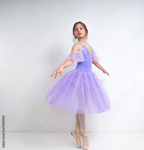 Young ballerina in a purple dress on a white background.
