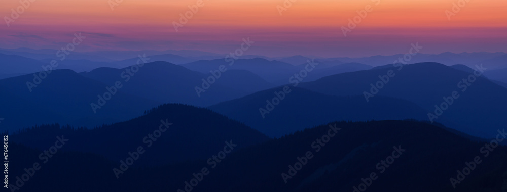 Panorama Silhouettes of Carpathian mountains in a natural blue-red gradient. Panorama of the Carpathian Mountains at dusk with silhouettes of ridges and peaks. Gorgany, Carpathians, Ukraine.