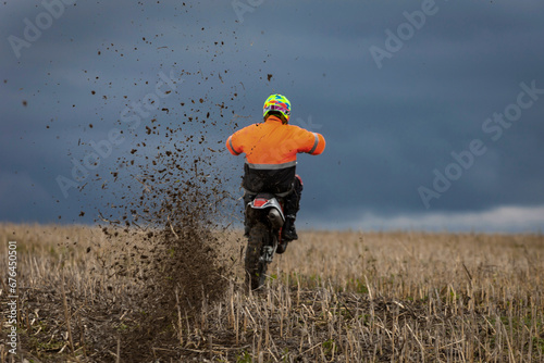 motocross dirtbike rider wheelie in field in front of dark blue sky 